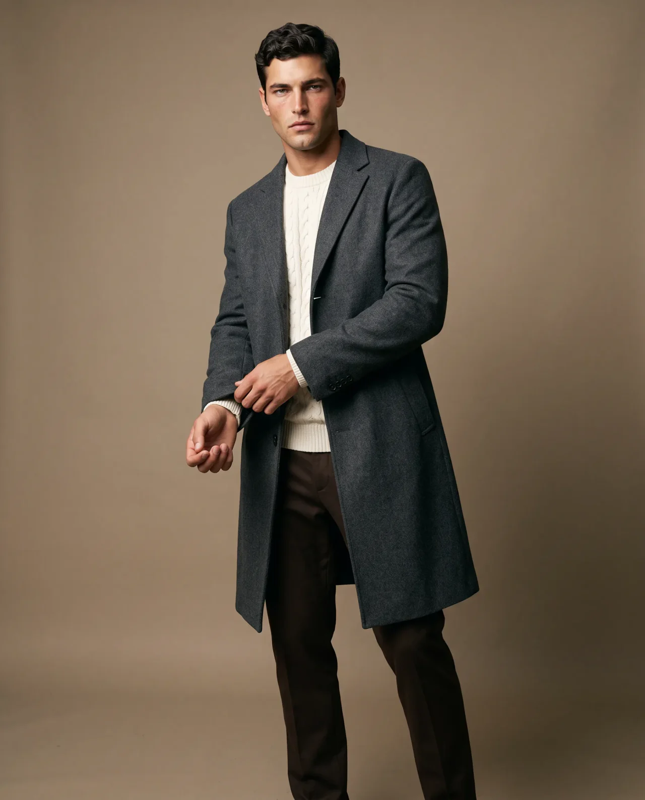 Liam in a charcoal overcoat and ivory knit against a warm taupe studio backdrop