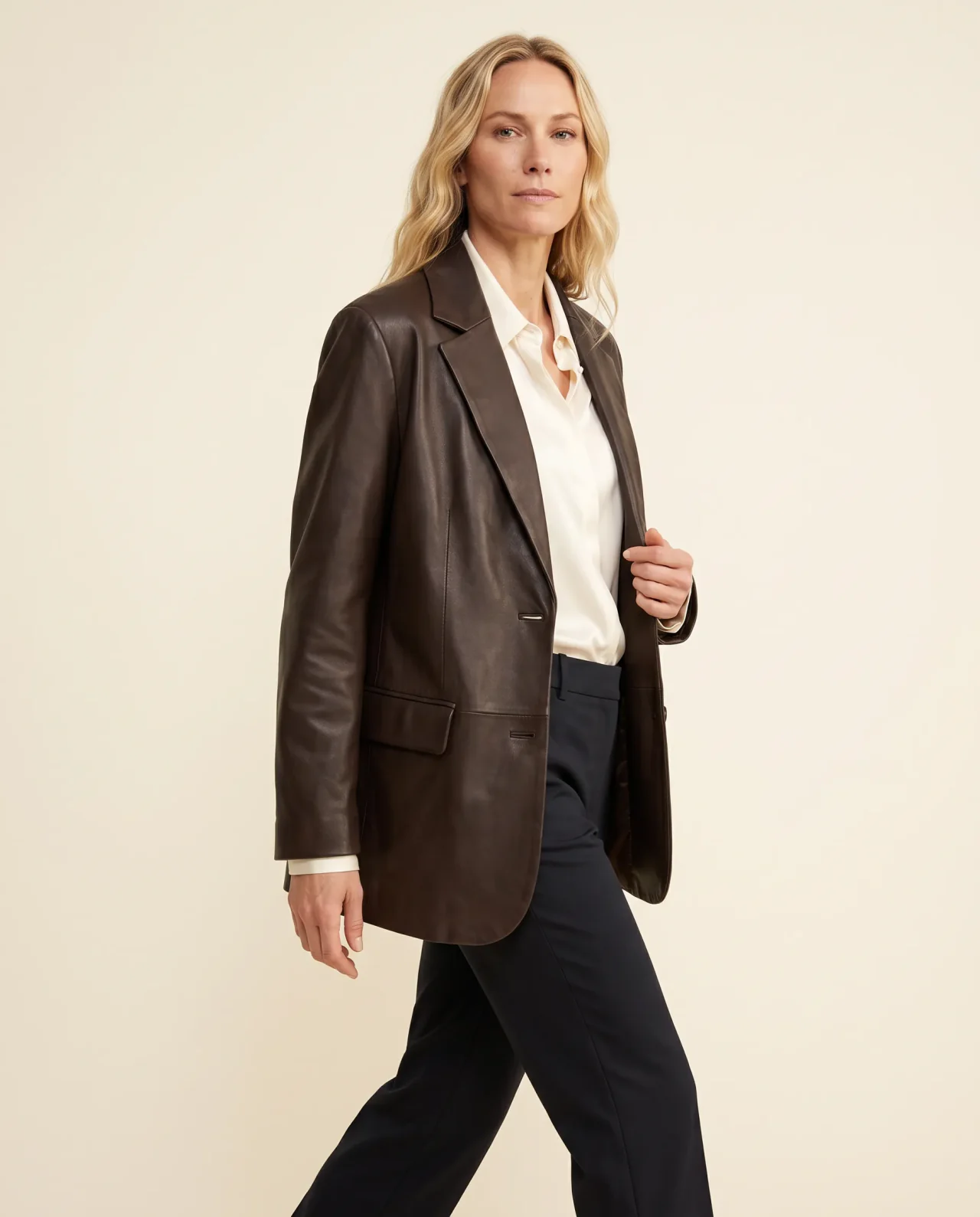 Melissa walking across an ivory studio in a chocolate jacket and tailored trousers